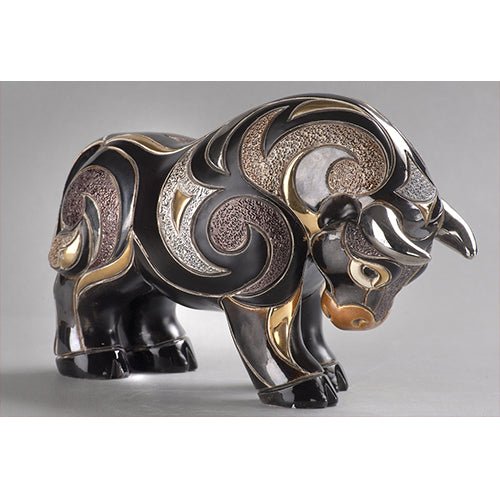 Hand‑carved red bull figurine with gold accents on shelf, symbol of strength and ambition. Uruguayan hand‑carved bull figurine. Rich red, black & gold finish. Symbolic strength artwork. Red & Gold Strength Sculpture.