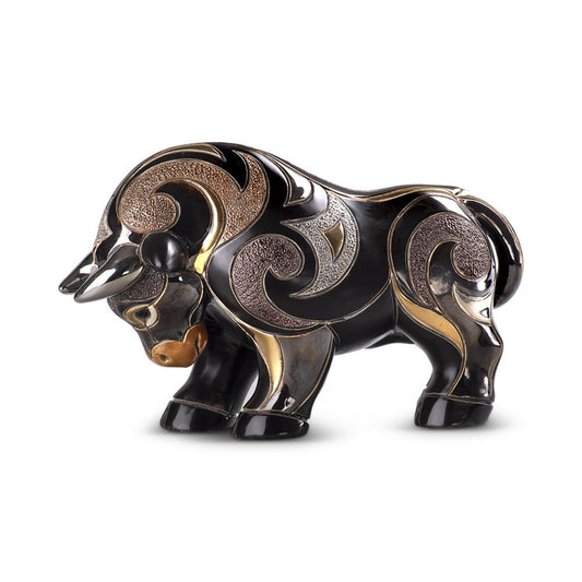 Hand‑carved red bull figurine with gold accents on shelf, symbol of strength and ambition. Uruguayan hand‑carved bull figurine. Rich red, black & gold finish. Symbolic strength artwork. Red & Gold Strength Sculpture.