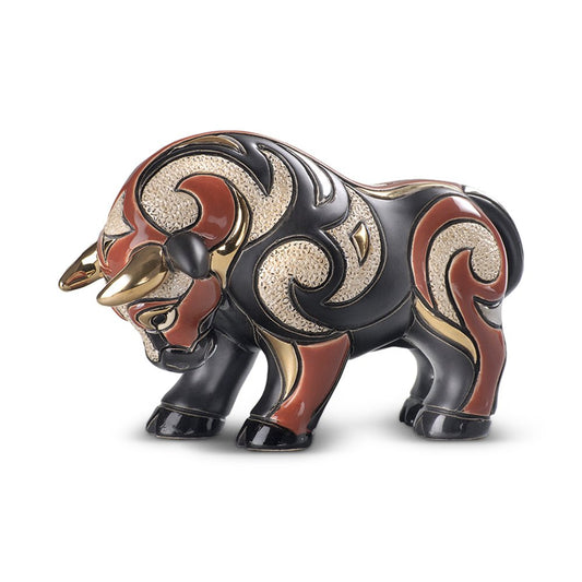 Hand‑carved red bull figurine with gold accents on shelf, symbol of strength and ambition. Uruguayan hand‑carved bull figurine. Rich red, black & gold finish. Symbolic strength artwork. Red & Gold Strength Sculpture.